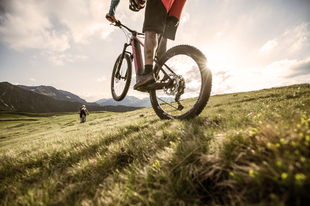 Mountainbiker auf einer Wiese im Gegenlicht