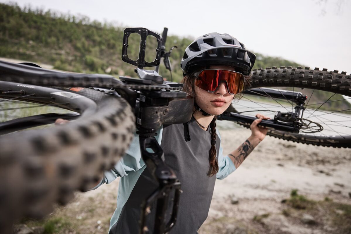 Fahrerin trägt ihr Bike auf der Schulter