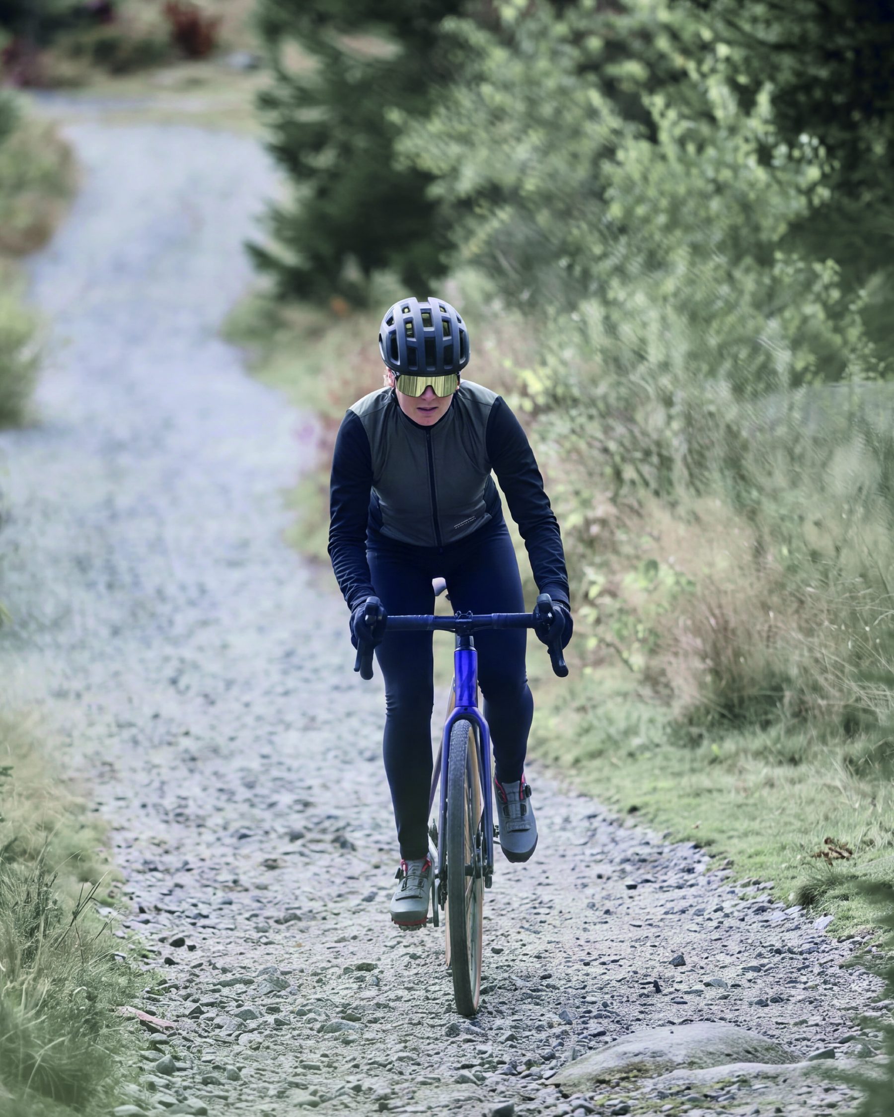 Gravel-Fahrerin auf einem Schotterweg durch den Wald