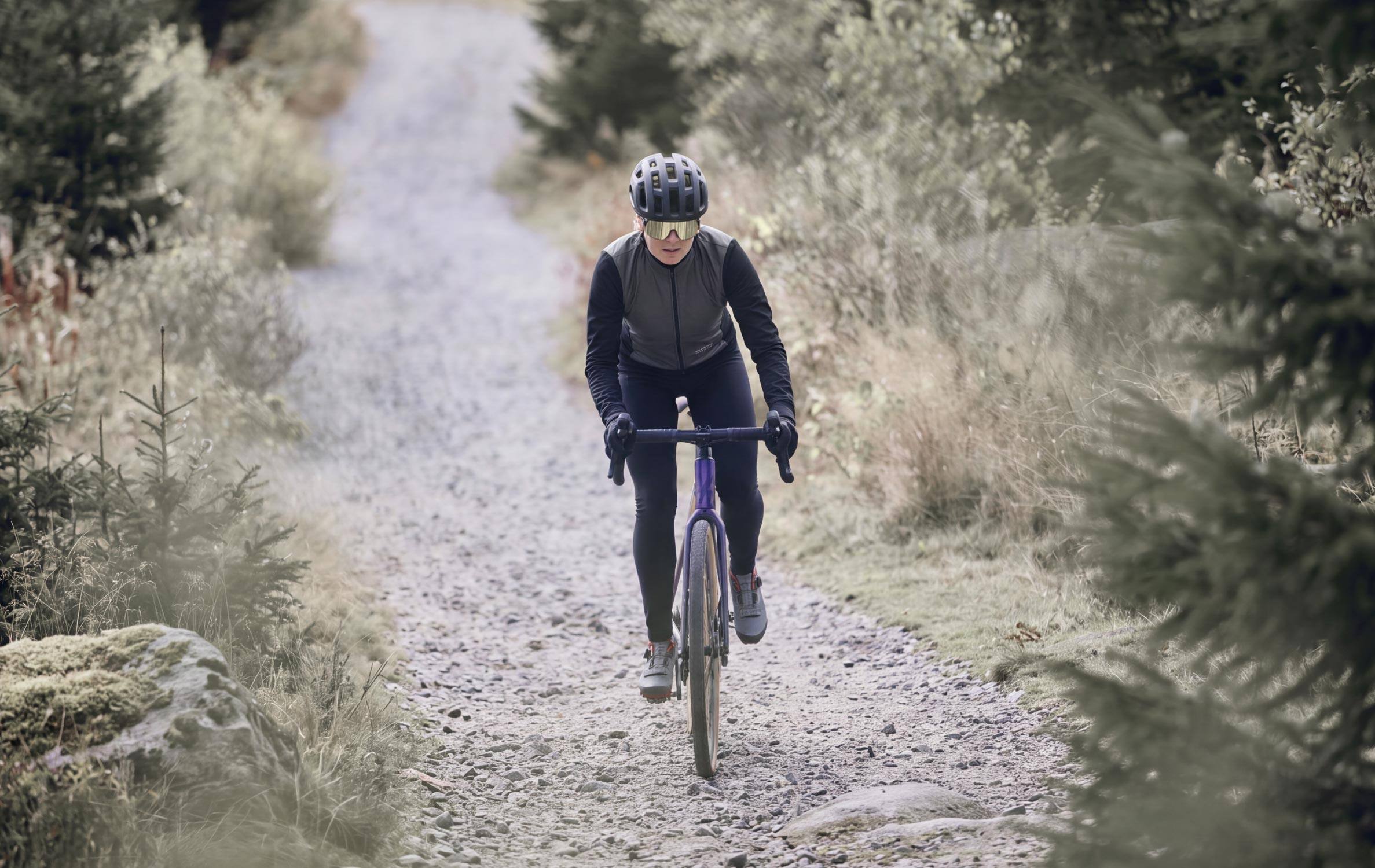Gravel-Fahrerin auf einem Schotterweg durch den Wald