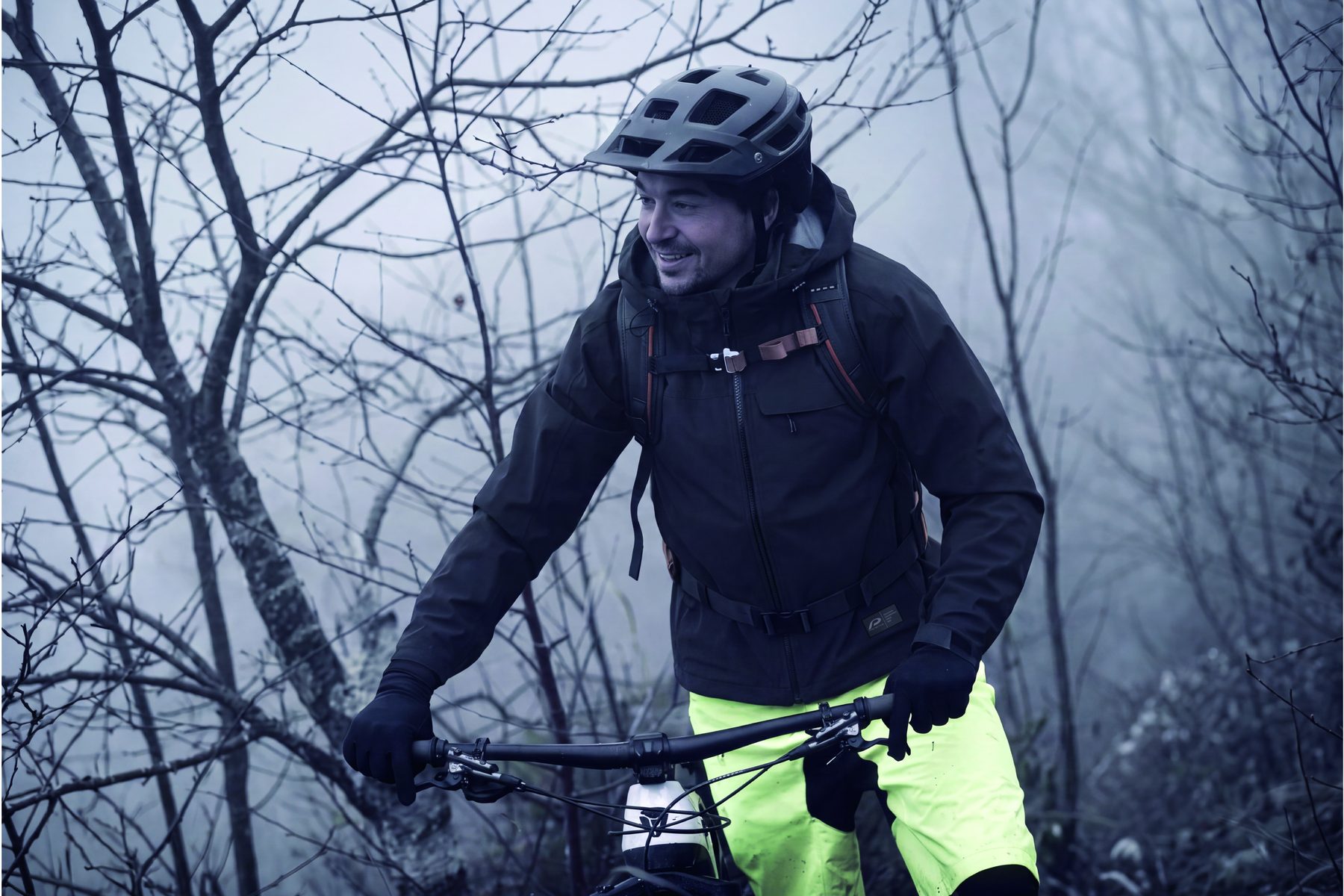 Mountainbiker in Regenjacke im Nebelwald
